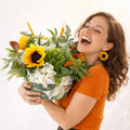 Woman holding a bouquet of flowers and laughing against a white background